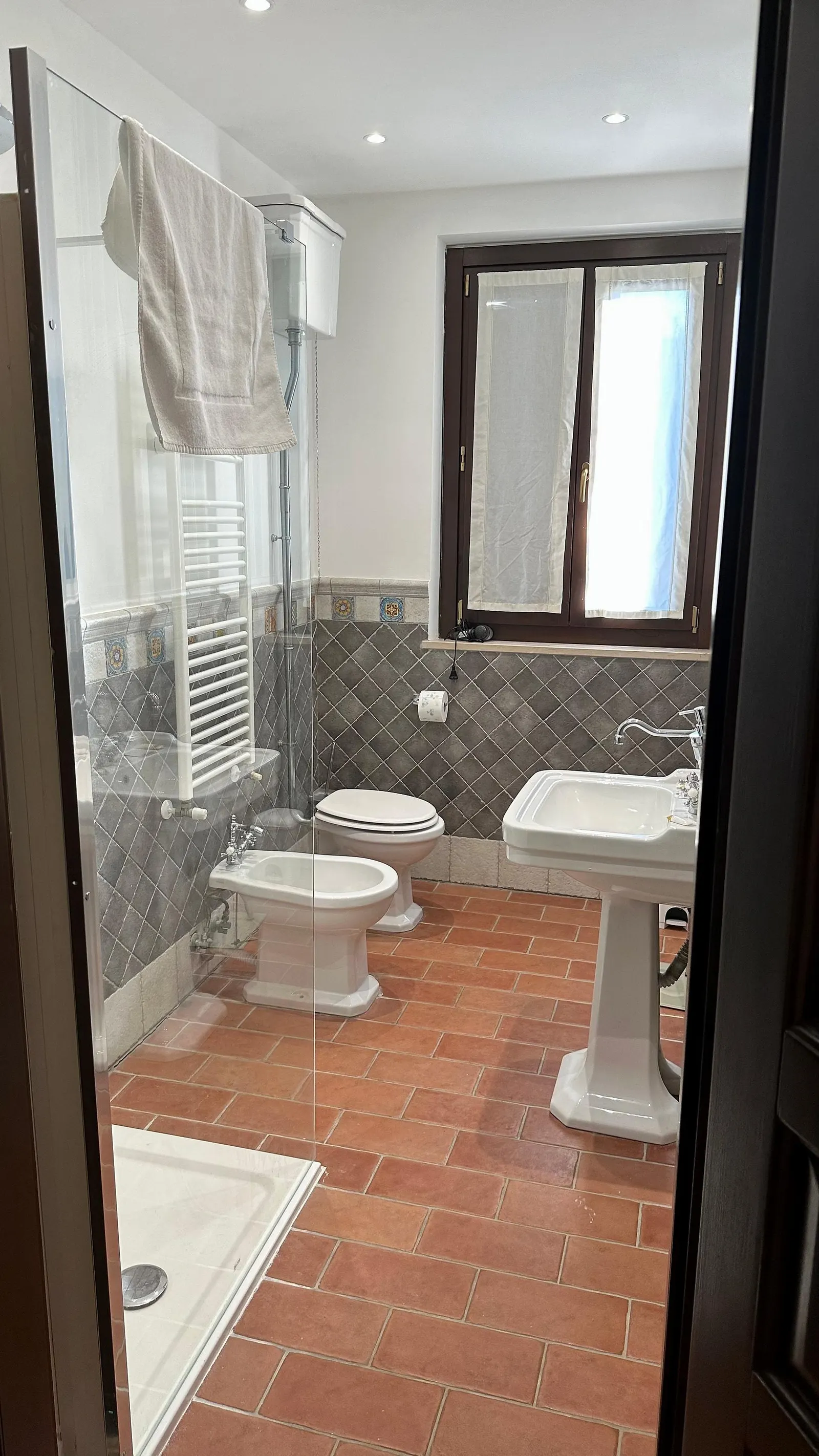 Bagno privato con doccia in vetro, cotto e maioliche