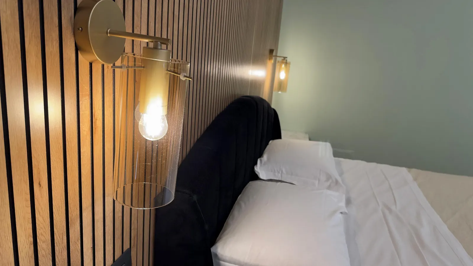 Dettaglio delle lampade in ottone sulla boiserie della testiera