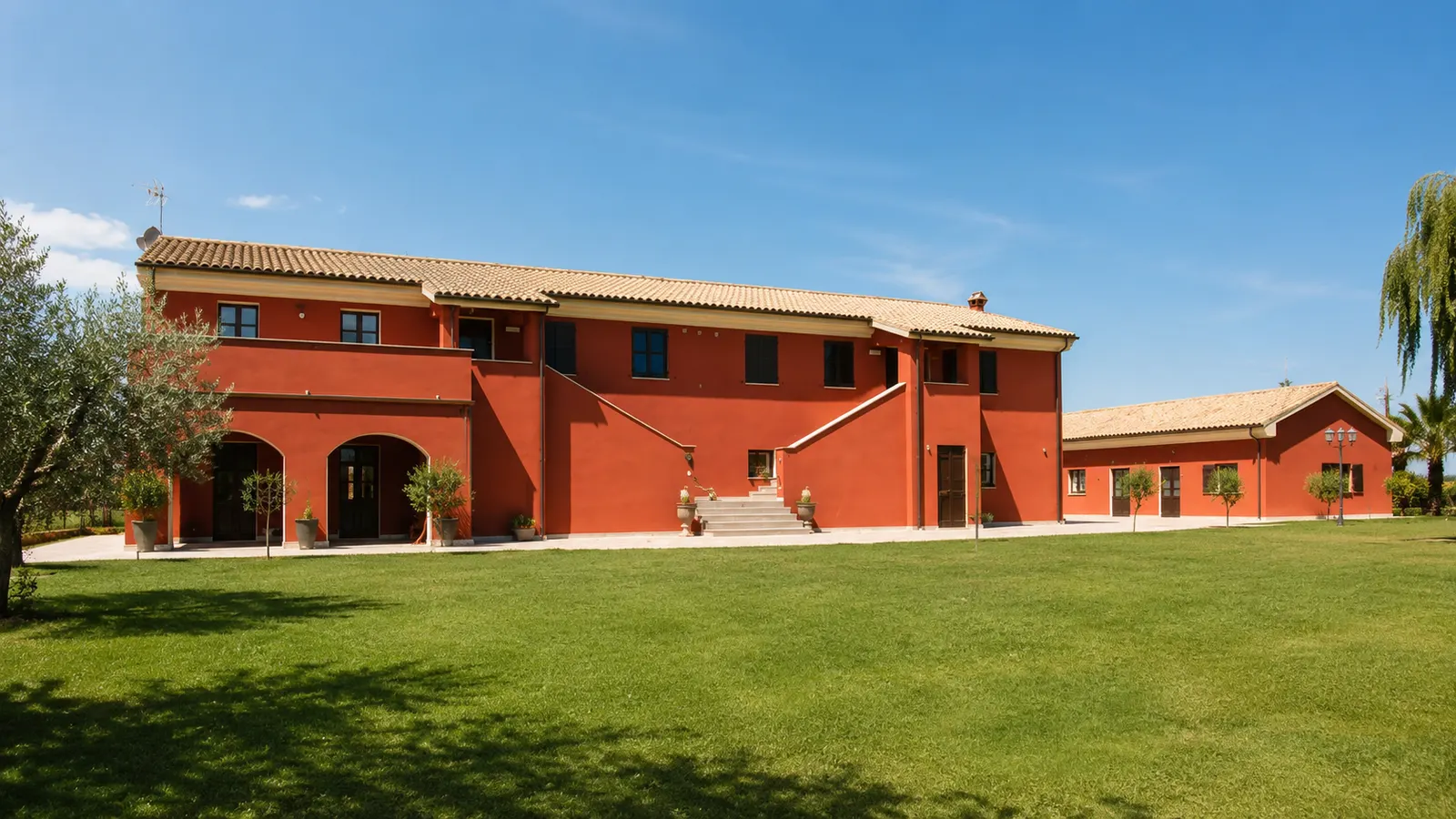 Il casale rosso di Don Chisciotte con il prato e gli ulivi